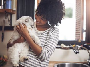 Woman cuddles cat in kitchen