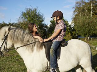 Mother helping son with horse riding